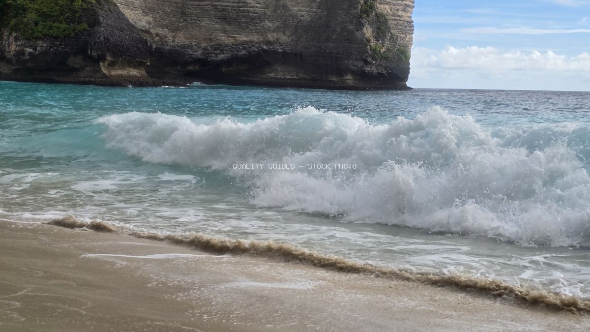 Kelingking Beach Bali with dramatic volcanic cliffs, turquoise ocean waves, and white sand beach - stock photo