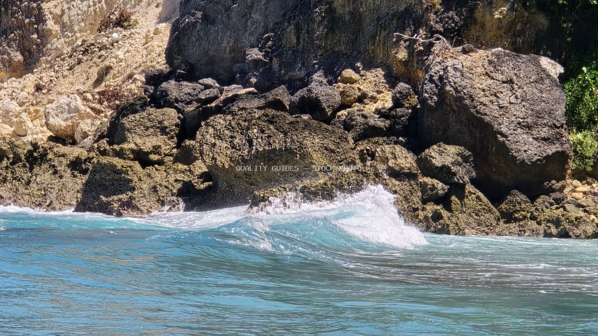 Turquoise waves crashing against rocky cliffs and boulders at Diamond Beach, Bali, Indonesia - stock photo