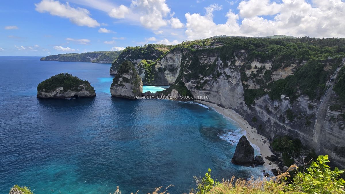 Aerial view of Diamond Beach Bali with turquoise waters, white sand, and dramatic limestone cliffs covered in tropical vegetation - stock photo