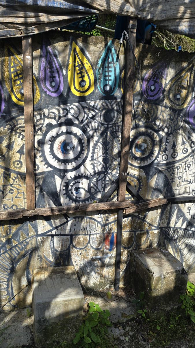 Colorful decorated surfboards hanging on wooden rack at Suluban Beach Bali with artistic tribal designs and bright yellow, purple, and cyan patterns - stock photo