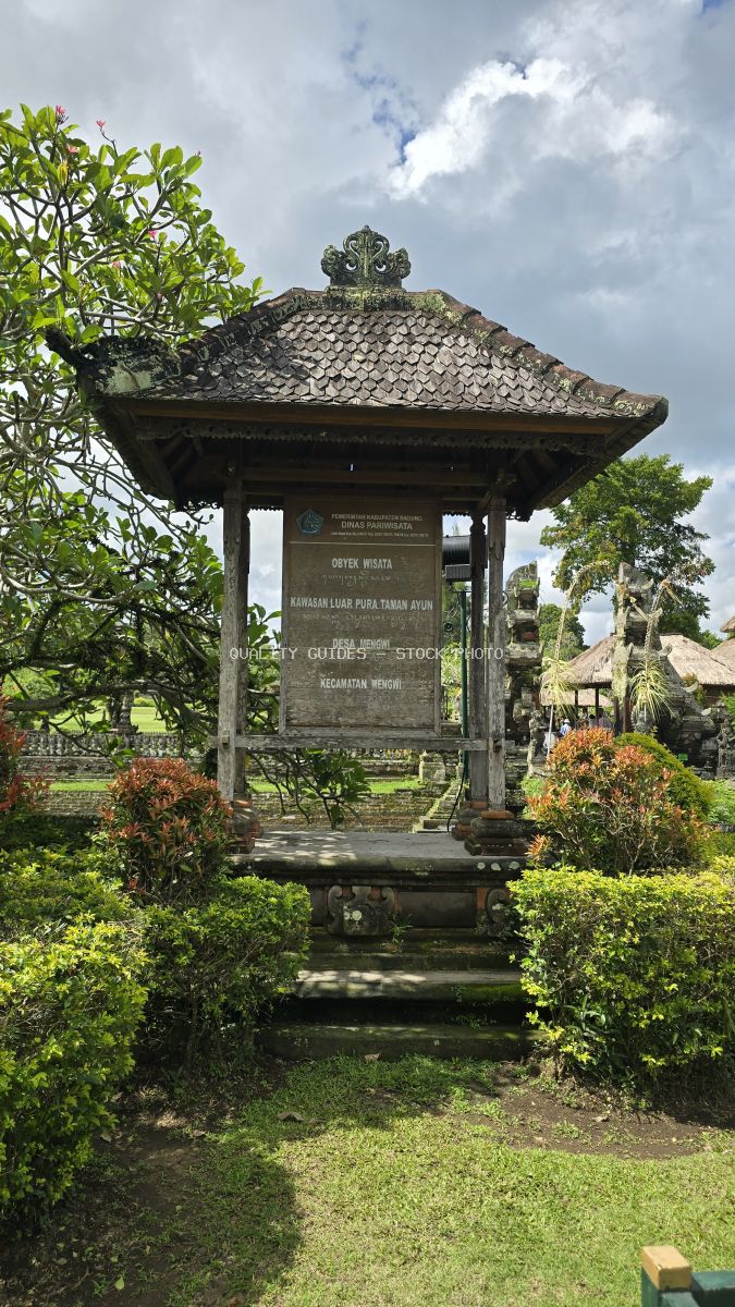 Traditional Balinese temple pavilion with ornate tiled roof and stone finials surrounded by tropical gardens at Taman Ayun Temple, Bali - stock photo