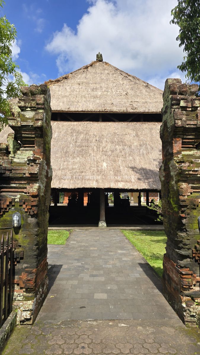 Traditional Balinese temple gateway with stone pillars and thatched roof at Taman Ayun Temple, Bali - stock photo