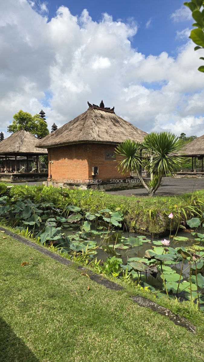 Traditional Balinese temple with thatched roof, tropical gardens, and lily pond at Taman Ayun Temple in Bali - stock photo