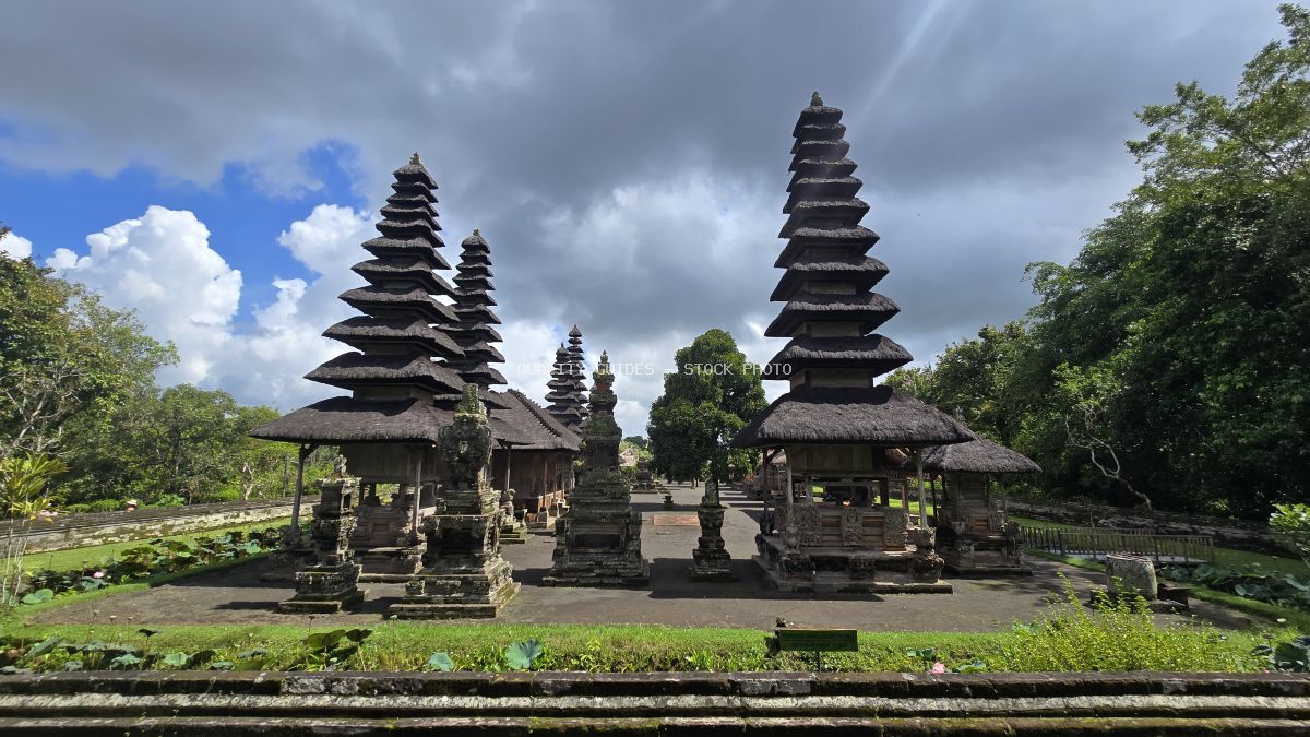 Twin black pagodas of Taman Ayun Temple in Bali with tropical gardens and dramatic sky - stock photo