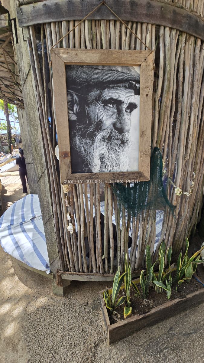 Weathered wooden frame with black and white portrait of bearded man on rustic wooden wall at Bali beach club - stock photo