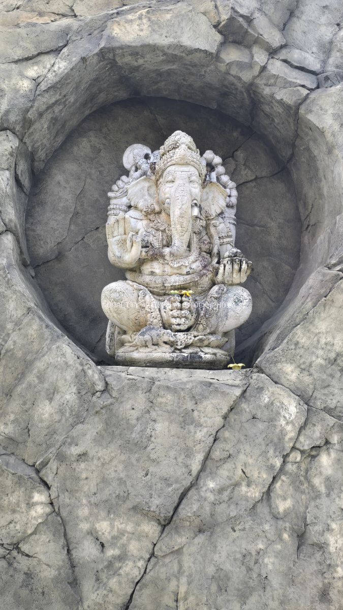 Carved stone Ganesha statue in circular niche at Bali temple shrine - stock photo