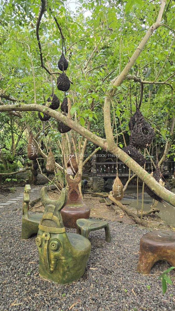 Wooden elephant sculptures and traditional Balinese art under lush green tree canopy at Nuanu Creative City, Bali - stock photo