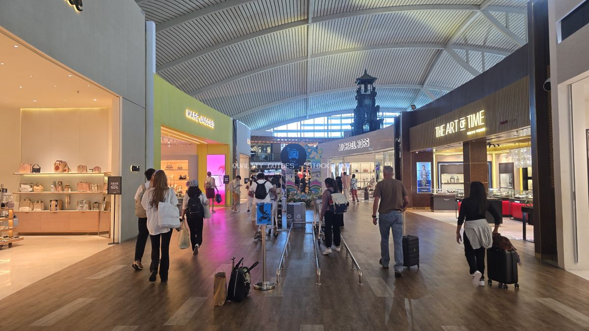 Busy modern airport terminal shopping corridor with travelers and duty-free stores at Bali International Airport - stock photo