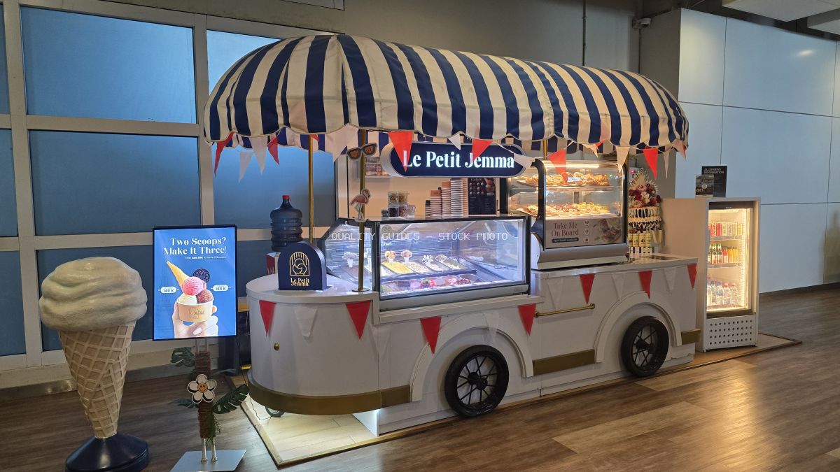 Vintage ice cream cart with striped awning in Bali airport terminal, displaying Le Petit Jemma brand products - stock photo