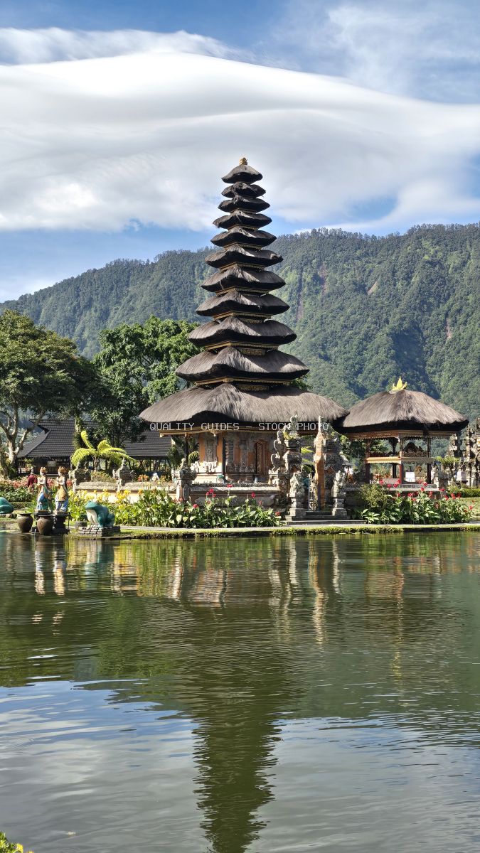 Ulun Danu Beratan Temple reflected in lake with forested mountains, Bali Indonesia - stock photo