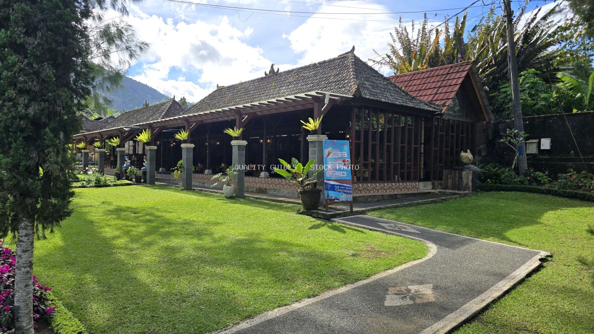 Ulun Danu Beratan Temple in Bali with traditional wooden architecture, yellow flowers, and manicured gardens - stock photo