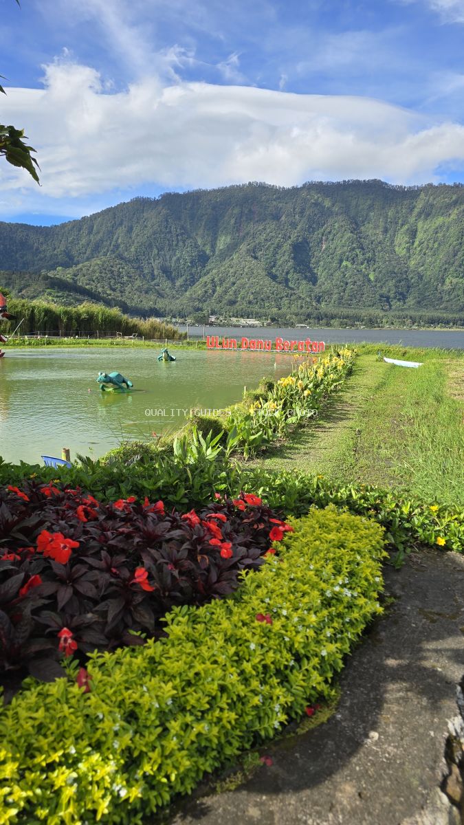 Ulun Danu Beratan Temple lake view with red flowers, green mountains, and traditional temple structures in Bali - stock photo