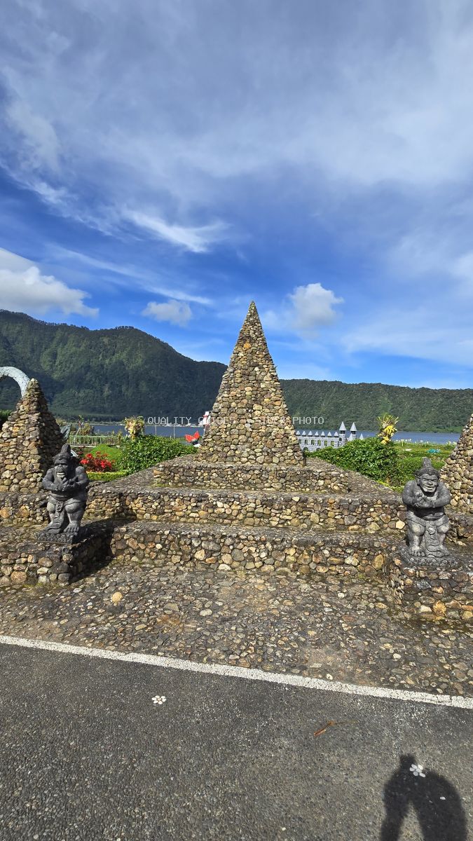 Stone shrine with guardian statues at Ulun Danu Beratan Temple overlooking Beratan Lake and mountains in Bali - stock photo