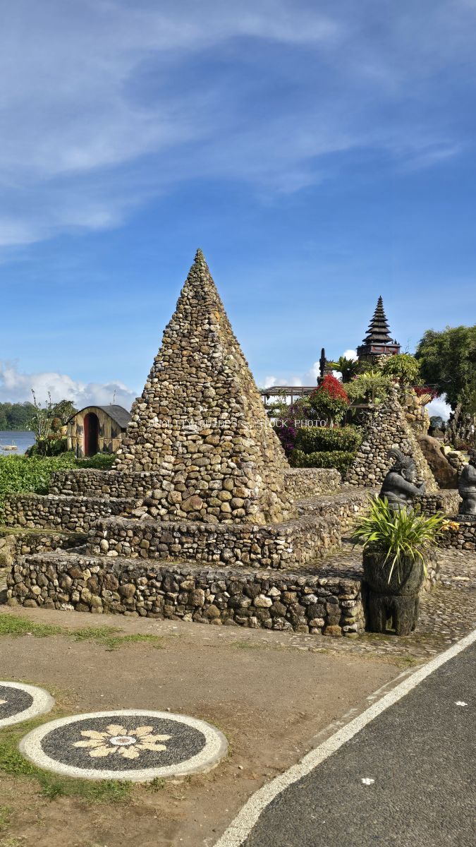 Stone pyramid structures at Ulun Danu Beratan Temple in Bali with lake and tropical vegetation - stock photo