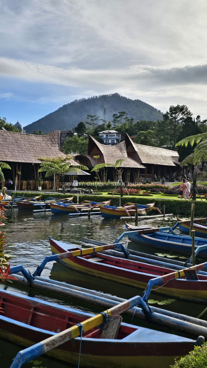 Colorful traditional boats on lake at Ulun Danu Beratan Temple in Bali with mountain backdrop - stock photo