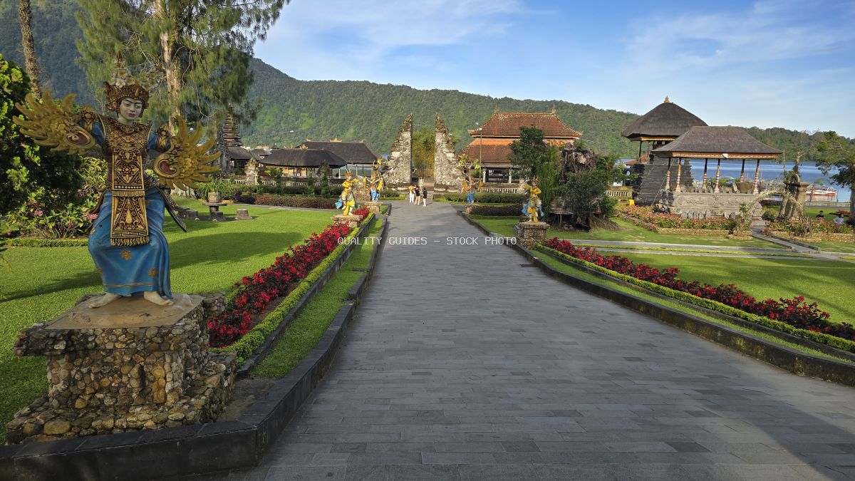 Ulun Danu Beratan Temple in Bali with symmetrical pathway, red flowers, and lake view - stock photo