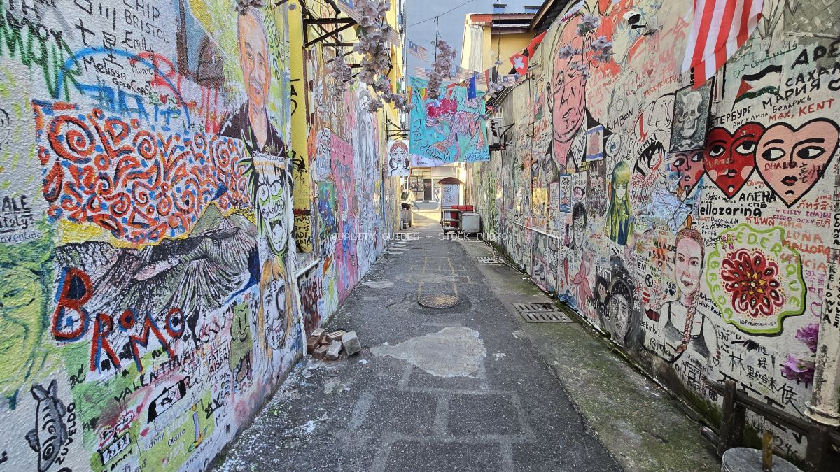 Colorful street art and graffiti covering both walls of a narrow urban alley in Kwai Chai Hong, Kuala Lumpur - stock photo