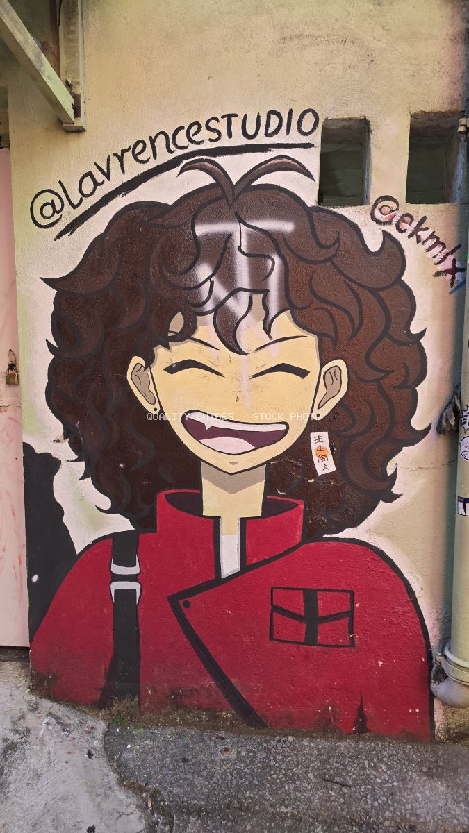 Colorful street art mural of smiling woman with curly brown hair in red jacket on weathered wall in Kuala Lumpur - stock photo
