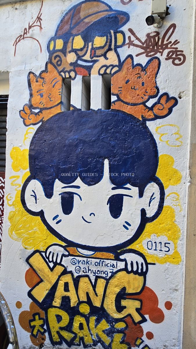 Colorful street art mural with cartoon character and orange cats on white wall in Kuala Lumpur - stock photo