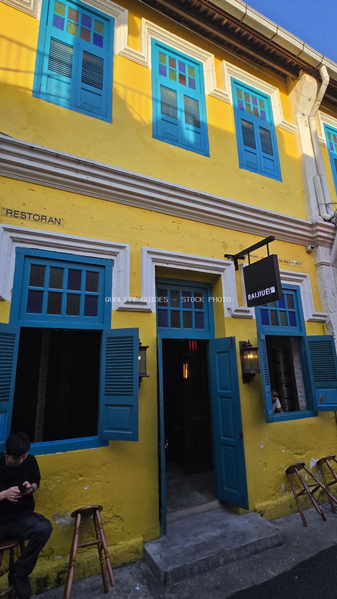 Bright yellow and blue colonial building at Kwai Chai Hong heritage site in Kuala Lumpur with traditional wooden shutters and storefronts - stock photo