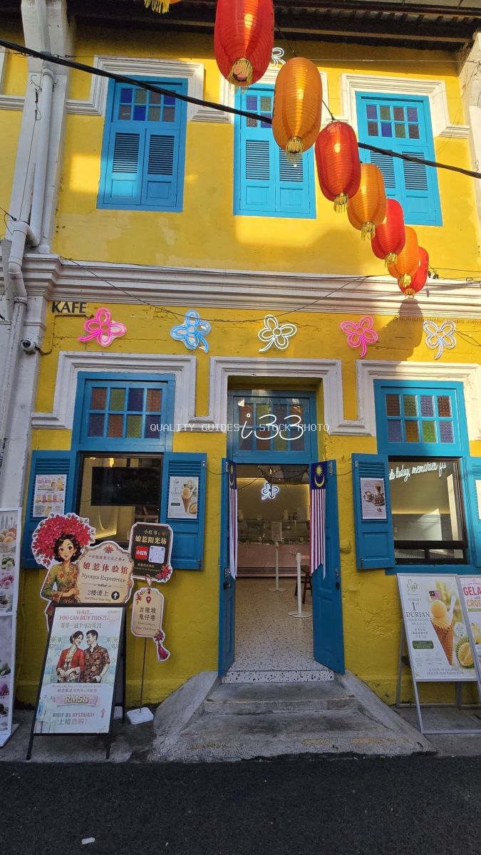 Bright yellow shophouse with blue windows and red lanterns at Kwai Chai Hong in Kuala Lumpur - stock photo