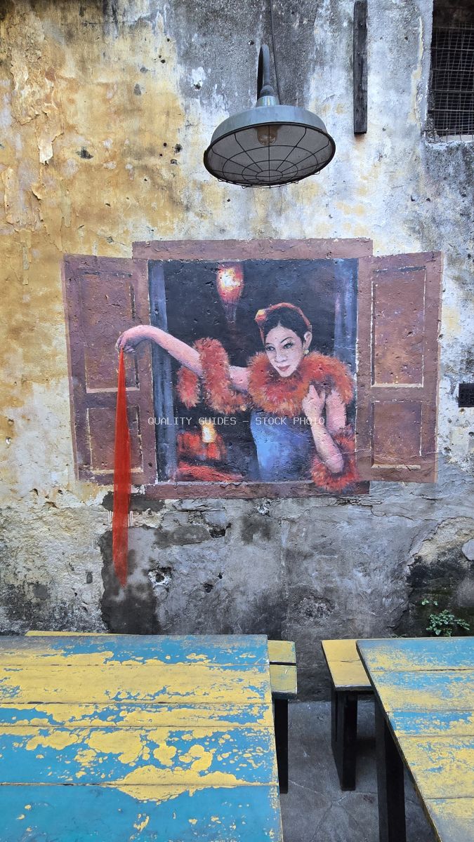 Colorful street art mural of woman in red feathers on weathered wall with vintage lamp, Kwai Chai Hong Kuala Lumpur - stock photo