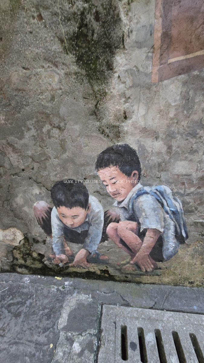 Street art mural of two children playing against weathered concrete wall in Kwai Chai Hong, Kuala Lumpur - stock photo