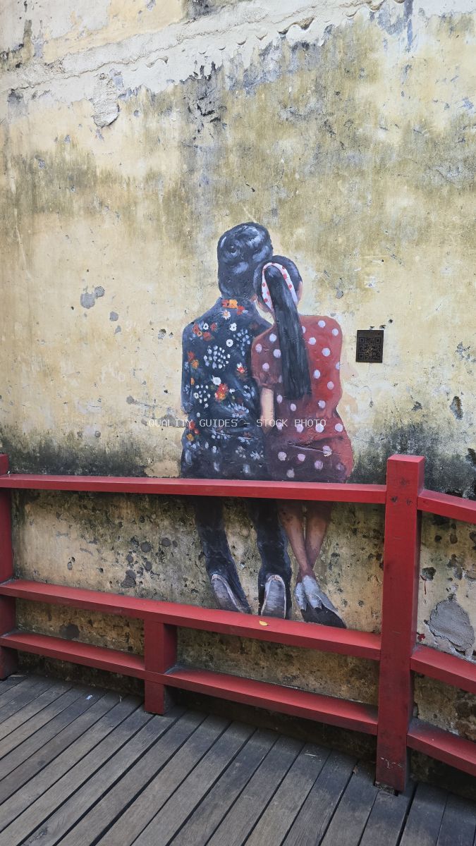 Street art mural of two women sitting on a bench painted on weathered wall above red wooden bench in Kuala Lumpur - stock photo