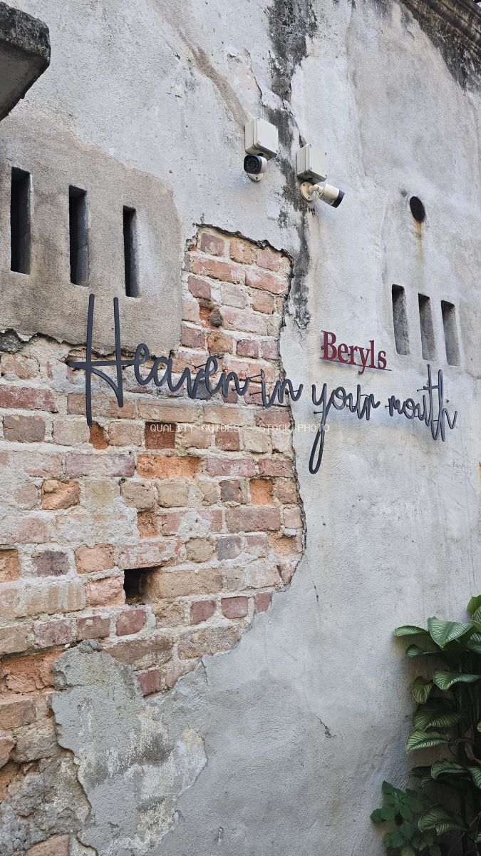 Weathered white wall with exposed red brick and street art text at Kwai Chai Hong heritage site in Kuala Lumpur - stock photo