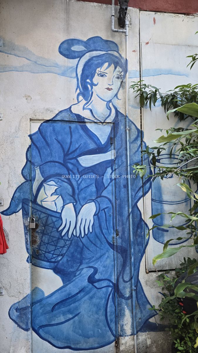 Blue street art mural of a woman on weathered wall with green plants, Kwai Chai Hong Kuala Lumpur - stock photo