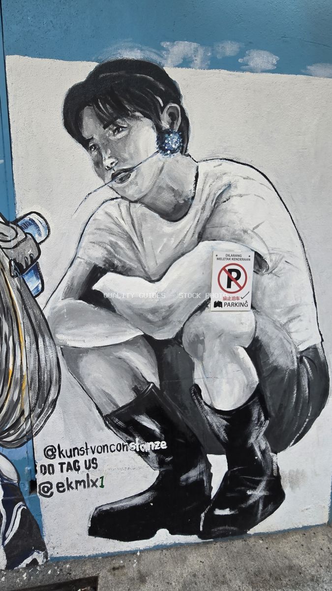 Black and white street art mural of crouching woman with no parking sign on chest, blue sky background, Kuala Lumpur - stock photo